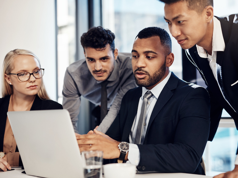 Shot of a group of young businesspeople using a laptop during a meeting in the boardroom of a modern office