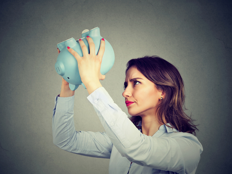 Young worried woman with empty piggy bank