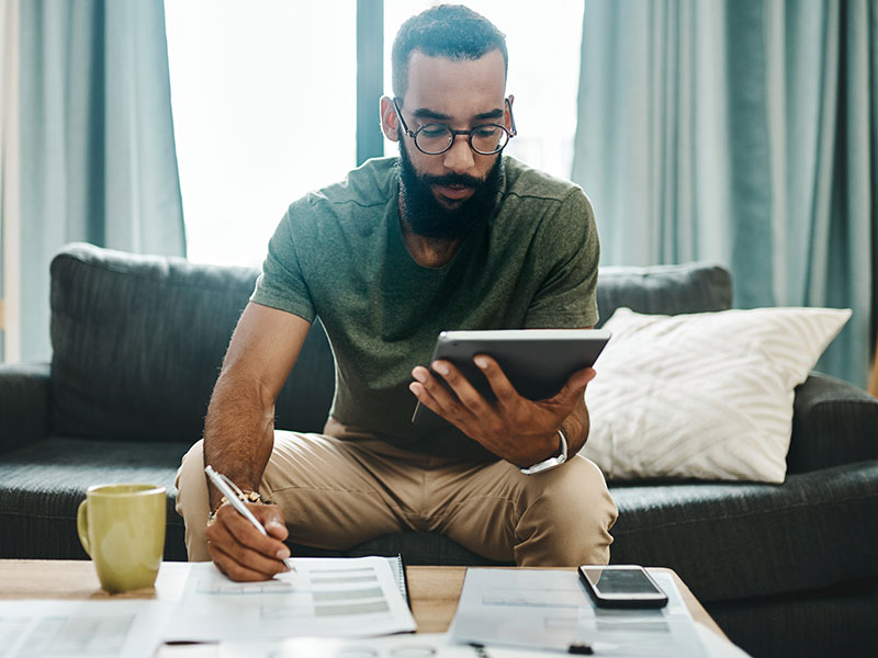 man reading tablet and writing on paper