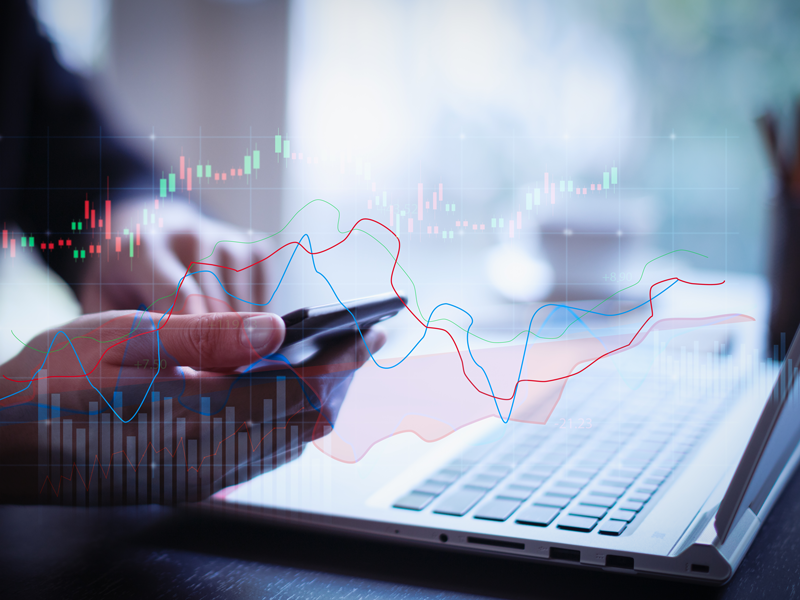 Financial charts overlaying user on laptop.
