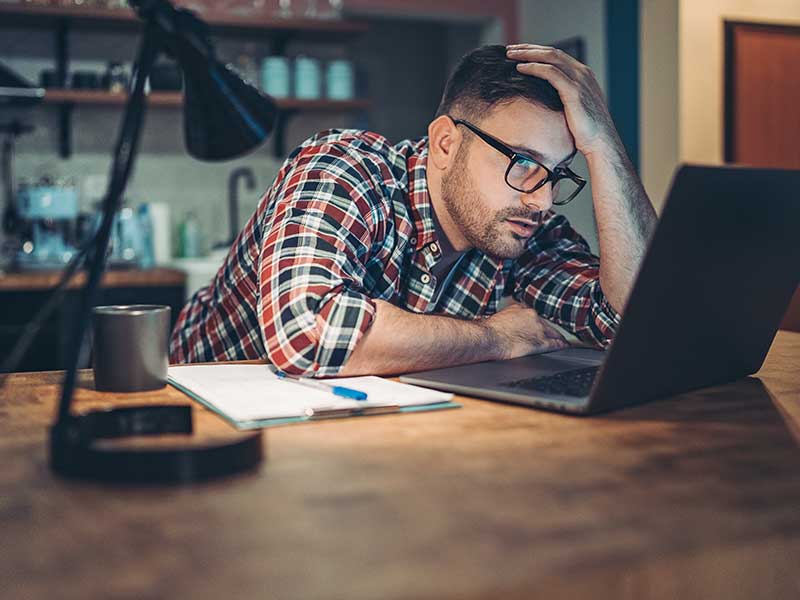 Man looking at a laptop in concern or frustration
