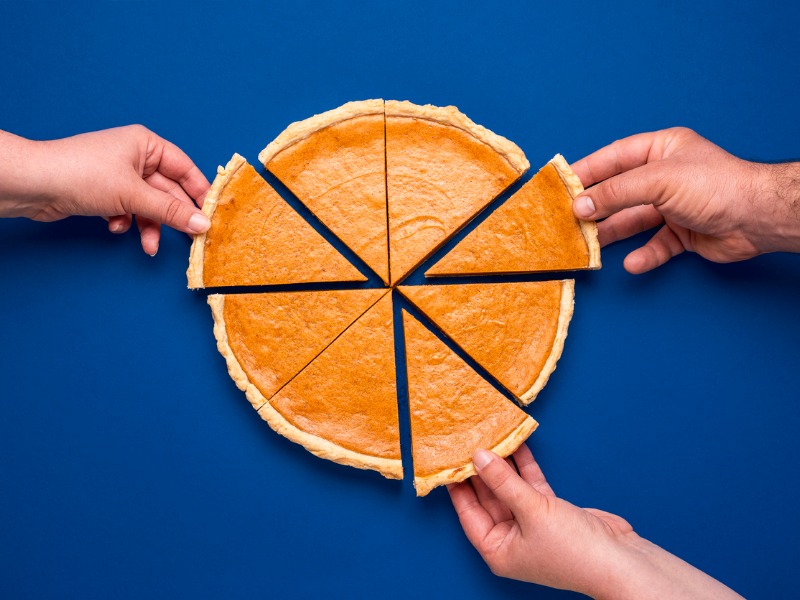 Sliced pumpkin pie above view on blue background. People grabbing slices of cake stock photo
