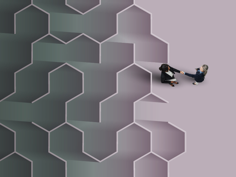 Women shaking hands next to a maze
