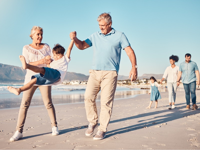 Grandparents walking with grandchild on the beach