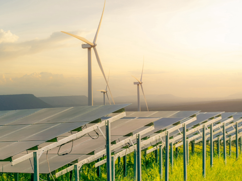 Image of solar and wind turbines farm, in a green field, representing sustainable energy and resources.